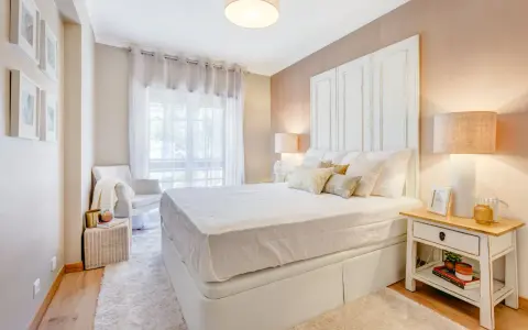 Camera da letto accogliente con letto bianco, comodino con libri e lampada. Idee su cosa mettere su como camera da letto.