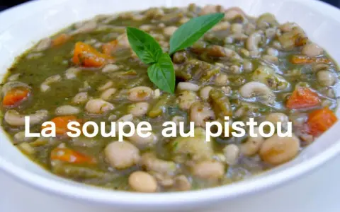 Un bol de soupe au pistou, garni de basilic frais, avec des haricots blancs, des pâtes et des carottes.