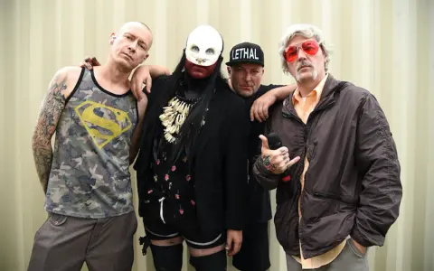 Członkowie Limp Bizkit, gotowi by break stuff, pozują do zdjęcia. Jeden w koszulce z Supermanem, drugi w masce, trzeci w czapce "Lethal", a czwarty z mikrofonem.