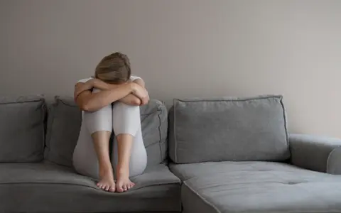 Kobieta z depresją siedzi skulona na kanapie, przygotowując się do komisji lekarskiej ZUS. Co mówić, by uzyskać pomoc?