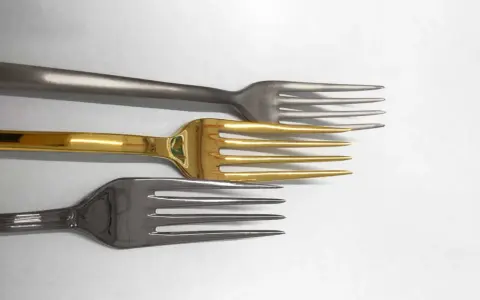 Tre forchette: una con finitura PVD oro, una grigia opaca e una grigia lucida, disposte in orizzontale.