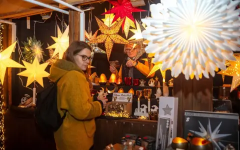 Besucherin auf einem velen Waldweihnachtsmarkt, umgeben von leuchtenden Sternen und weihnachtlicher Deko.