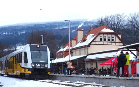 Pociąg GRYFC na stacji w Świeradowie-Zdroju, zimowy krajobraz z ośnieżonymi górami w tle.