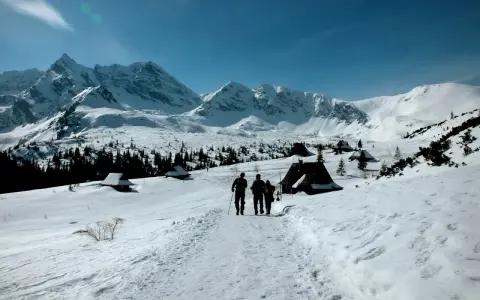 Trzej turyści idą szlakiem przez zasypane śniegiem Tatry. Widok idealny na tatry zimą dla średniozaawansowanych.