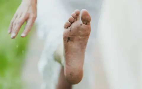 Pie sucio y descalzo, con tierra y hierba. Un consejo para como quitar el olor de los pies es lavarlos bien.