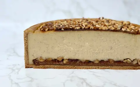 Tranche de flan praliné onctueux, garni de noisettes concassées et d'un coulis de caramel.