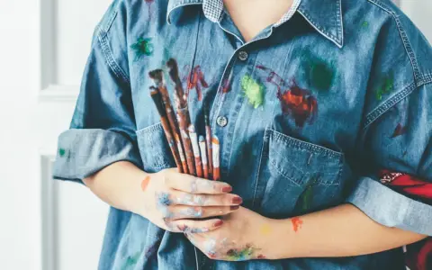 Manos manchadas de tempera y una camisa vaquera salpicada de pintura. ¡Un desafío para quitar tempera de la ropa!