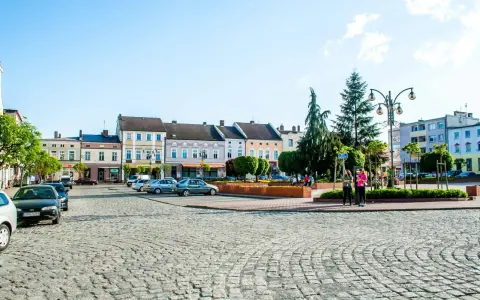 Rynek w Krapkowicach z kolorowymi kamienicami i brukowaną nawierzchnią. Atrakcje miasta widoczne w tle.