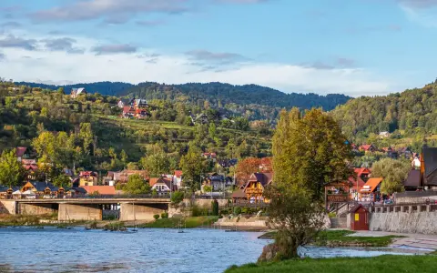Widok na malownicze ulice w Szczawnicy, z domami na zboczach gór i rzeką w tle.