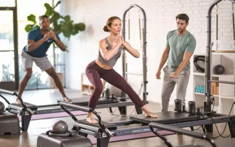 Persone che praticano pilates su reformer, un allenamento che migliora forza e flessibilità.