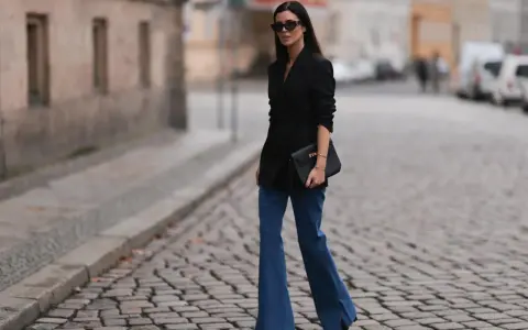 Stylische Frau in Schlaghosen und schwarzem Blazer. Ein tolles Beispiel, welche Oberteile zu Schlaghosen passen: elegant und modern.