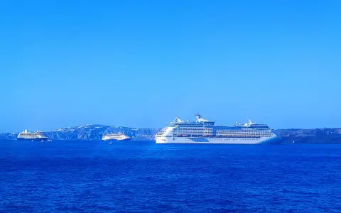 Grandi navi da crociera Royal Caribbean navigano in acque blu, con isole sullo sfondo.