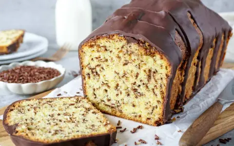 Ein saftiger, gesunder Kuchen mit Schokoladenstückchen und dunkler Glasur, daneben eine Scheibe und eine Schale Streusel.
