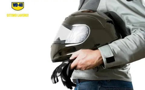 Un motociclista tiene un casco nero lucido e guanti. Scopri come pulire visiera casco per una guida sicura.