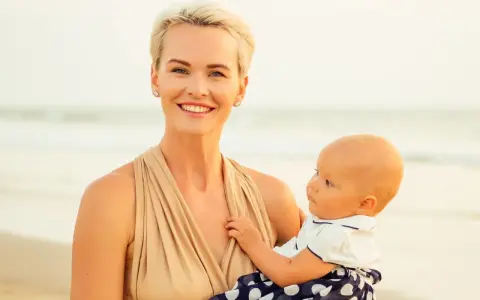 Uśmiechnięta mama z dzieckiem na plaży. Czas na nowe etapy, nawet jeśli to nagłe odstawienie od karmienia piersią.