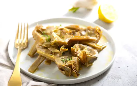 Carciofi cotti in olio e limone, pronti per essere serviti. Scopri come congelare i carciofi per averli sempre a disposizione.