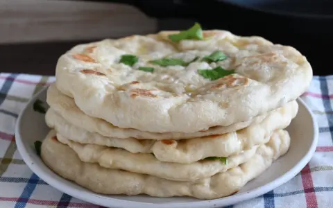 Pila di pane in padella, soffice e dorato, guarnito con erbe fresche. Perfetto per accompagnare ogni pasto.