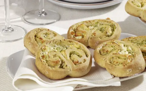 Zucchini Schnecken mit Käsefüllung auf einem Teller mit weißer Serviette.