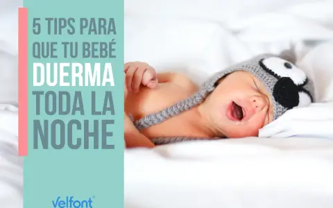 Un bebé con gorro de búho, con la boca abierta, en la cama. 5 consejos para que tu bebé duerma toda la noche.