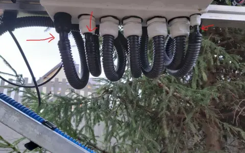 Przewody solarne w peszlu i bez, podłączone do skrzynki. Czerwone strzałki wskazują na połączenia.