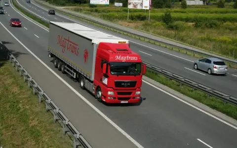 Czerwony tir Magtrans jedzie autostradą. Kierowca może otrzymać mandat za wyprzedzanie tirem w niewłaściwym miejscu.