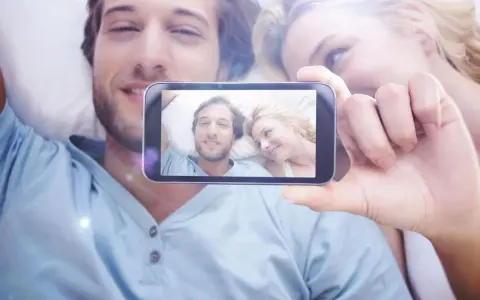 Para widzi na ekranie telefonu siebie, uśmiechnięci i blisko. To piękne objawy zauroczenia.