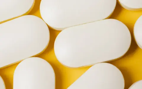 Bianche compresse ovali, disposte su sfondo giallo. Potrebbero essere un antibiotico azitromicina, utili per combattere infezioni batteriche.