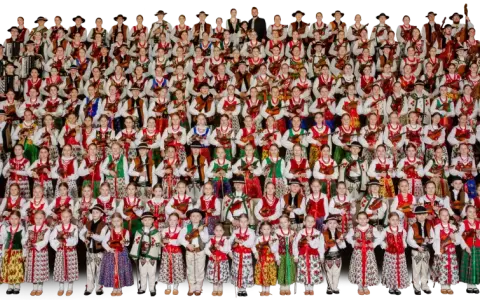 Wielka grupa dzieci i młodzieży w strojach ludowych, grających na akordeonach i skrzypcach. To piękna prezentacja muzyki ludowej Mazowsza.