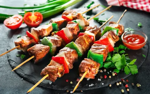 Spiedini di carne succulenti con peperoni e cipolle, pronti per essere gustati con una salsa rossa e pomodorini freschi.