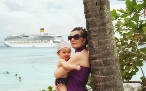 Mamma e bimbo abbracciati vicino a una palma, con una nave da crociera all'orizzonte. Una splendida posizione costa pacifica.