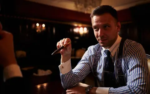 Mężczyzna w eleganckiej koszuli i krawacie trzyma pióro, zastanawiając się, ile bierze adwokat za reprezentowanie w sądzie.