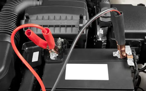 Jumper cables connected to a car battery. Learn how long to leave jumper cables on for a successful jump start.