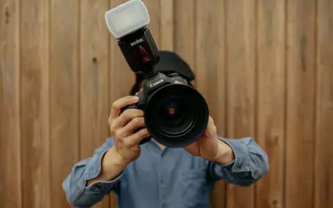 Fotograf trzyma aparat Canon z lampą błyskową. Liczba przewodnia lampy błyskowej jest kluczowa dla uzyskania idealnego oświetlenia.