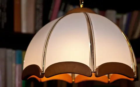 Elegancki abażur z materiału, ozdobiony złotymi paskami i drewnianymi elementami. Idealny do salonu, inspiracja jak zrobić abażur z materiału.