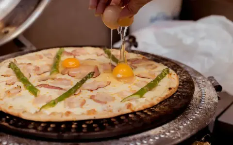 Na pizzę z boczkiem i szparagami dodawane jest jajko.
