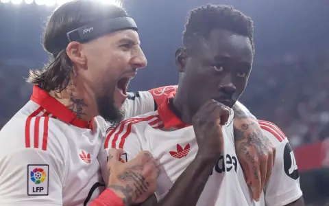 Jugadores del Sevilla FC celebran un gol contra el Atlético de Madrid. Uno grita con euforia, el otro reflexiona.
