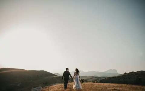 Para młoda idzie przez wzgórza, jak w pięknych cytatach o małżeństwie. Słońce zachodzi, tworząc magiczną atmosferę.