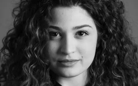 Primo piano di una giovane donna con capelli ricci, un esempio di diversi tipi di ritratto che catturano espressioni uniche.