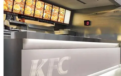 Mostrador de KFC con menú digital y cartel de "0". El food court significado es un área de comida.