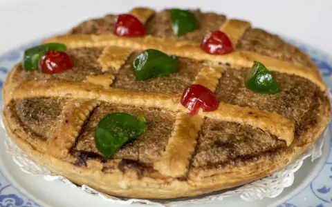 Tarta de Mondoñedo, un dulce tradicional con masa dorada, relleno de frutos secos y decorada con cerezas rojas y verdes.