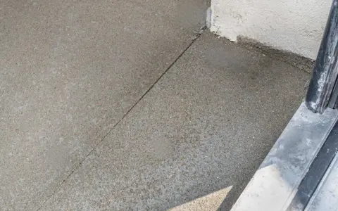 Dylatacja betonu na zewnątrz, widoczna linia podziału na świeżo wylanej nawierzchni, zapobiegająca pękaniu.