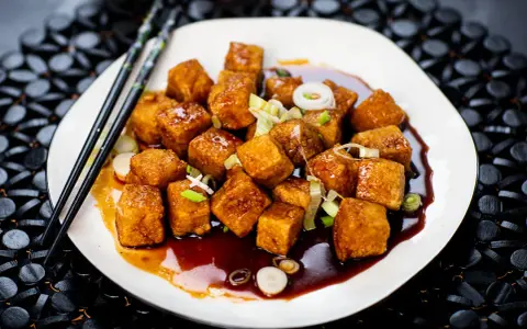 Krispiga, glaserade tofubitar med salladslök och en mörk sås. Ett läckert tofu recept som ser fantastiskt ut!