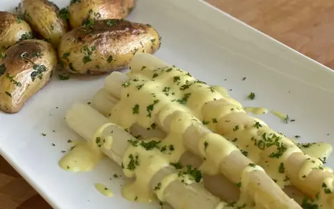 Weißer Spargel mit Kartoffeln und cremiger, veganer Hollandaise, bestreut mit frischer Petersilie. Ein Genuss!