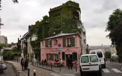Urokliwa ulica na Montmartre z różową kawiarnią La Maison Rose i budynkiem porośniętym bluszczem.