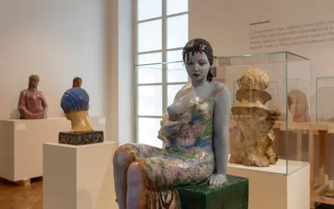 Ceramiczna rzeźba kobiety w kwiecistej sukni, dzieło inspirowane twórczością Olgi Niewskiej, prezentowana w muzeum.