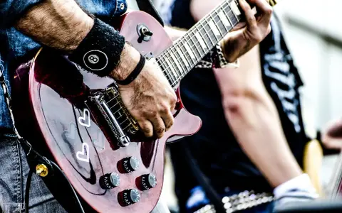 Muzyk gra na gitarze, przygotowując się do wykonania coverów piosenek.