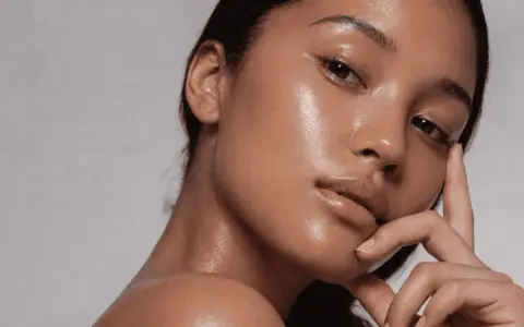 Rostro de mujer con piel glowy, hidratada y radiante. Su mano acaricia suavemente su barbilla.