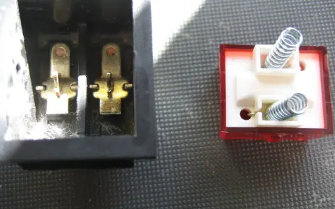 Detalle del interruptor de paso por dentro: contactos metálicos en un lado y resortes en el otro, listos para conectar.