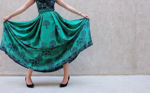Abito color ottanio con fantasia di alberi. Scarpe nere eleganti completano il look.