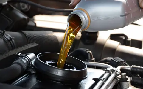 Verser de l'huile minérale ou synthétique dans le moteur d'une voiture.